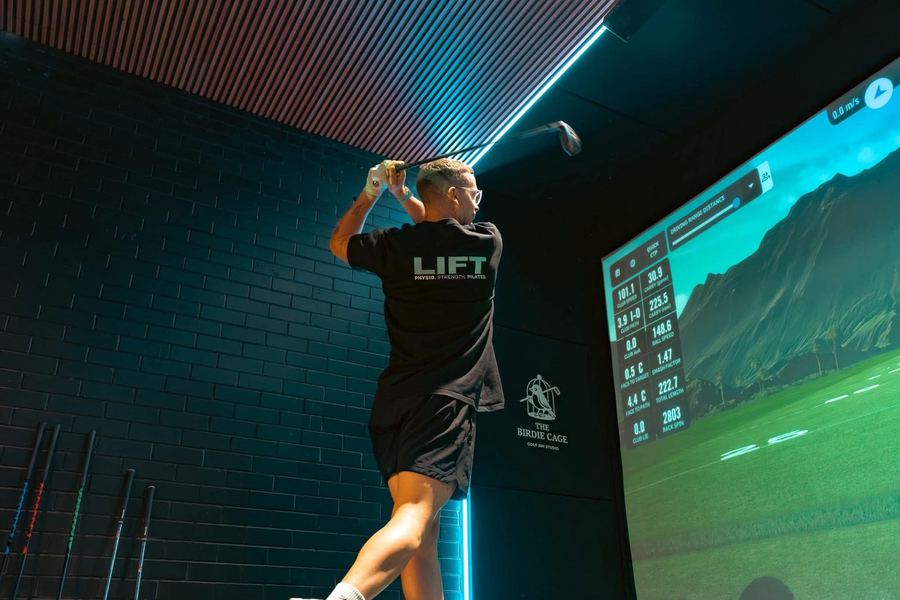 Josh hitting a driver in the golf simulator at The Birdie Cage