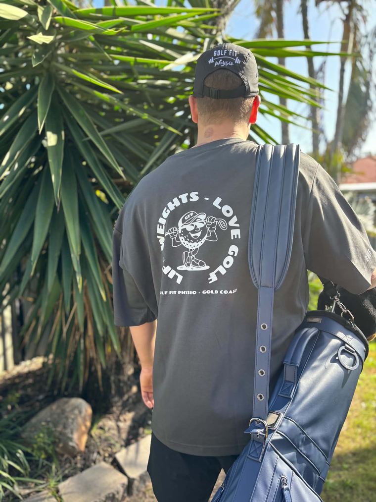 A golfer in a Golf Fit Physio shirt reading Lift Weights, Love Golf, carrying a golf bag